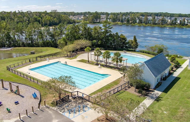 view of swimming pool featuring a patio, a water view, and a lawn