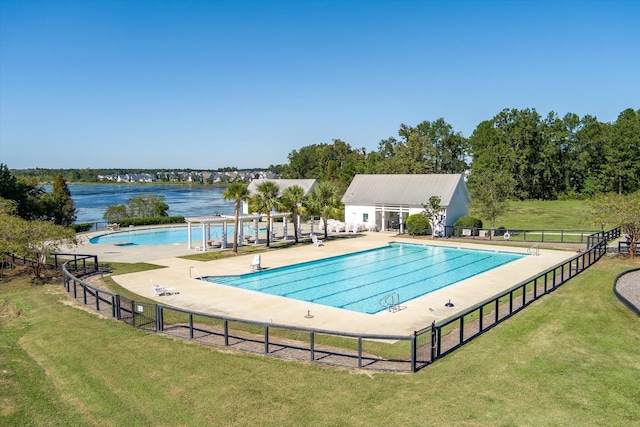 view of pool with a patio area, a water view, and a lawn