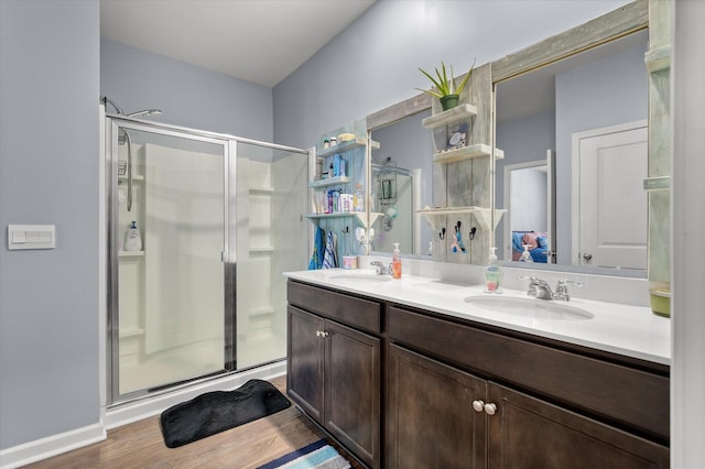 full bath featuring double vanity, wood finished floors, a stall shower, and a sink