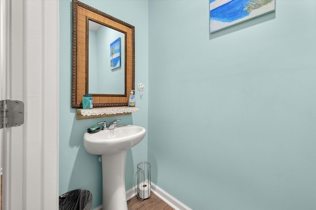 bathroom featuring wood finished floors, baseboards, and a sink