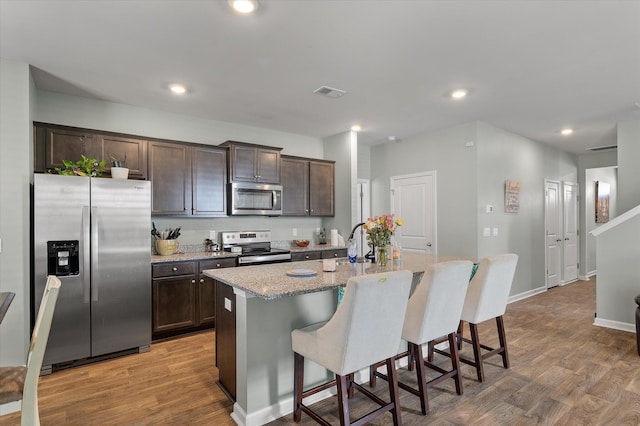 kitchen featuring visible vents, dark brown cabinetry, appliances with stainless steel finishes, and light wood-style flooring