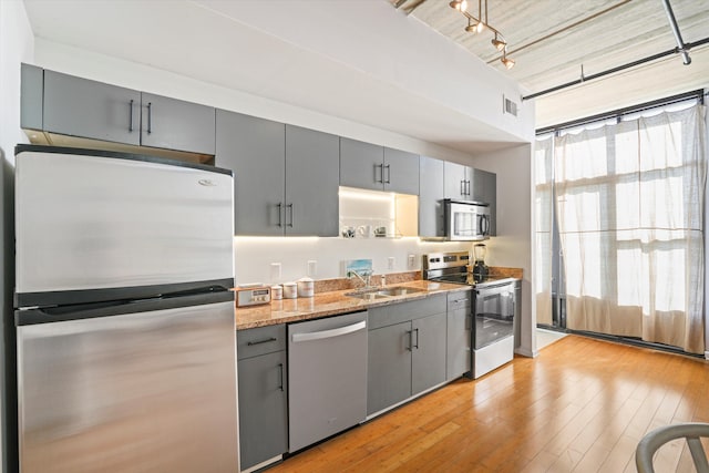 kitchen featuring visible vents, gray cabinets, light stone counters, a sink, and appliances with stainless steel finishes