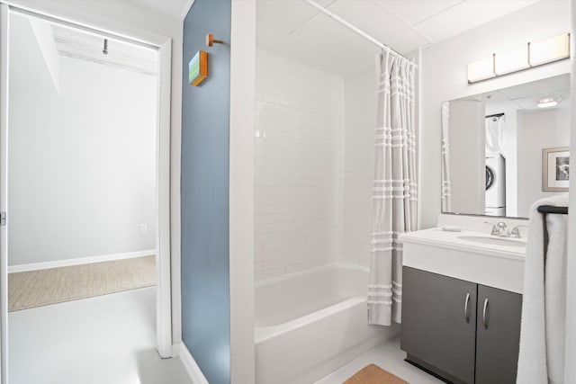 full bathroom featuring vanity, baseboards, stacked washer / dryer, and shower / tub combo