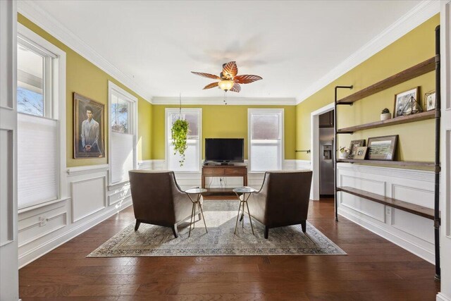 living area with dark wood finished floors, crown molding, and wainscoting