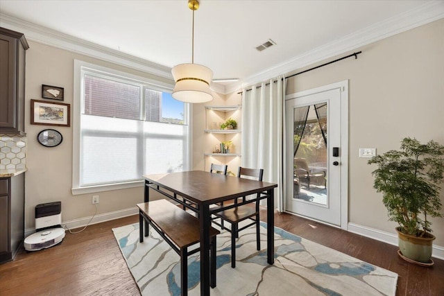 dining room with baseboards, wood finished floors, visible vents, and ornamental molding