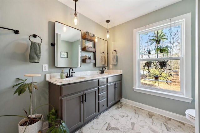 bathroom with double vanity, marble finish floor, baseboards, and a sink