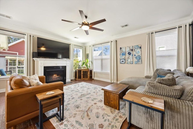 living room with visible vents, a fireplace with flush hearth, dark wood-style floors, and crown molding