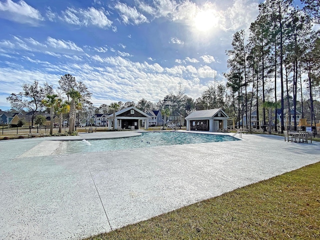 community pool with a patio, fence, and an outdoor structure