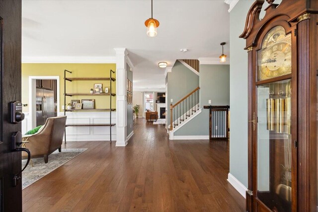 entryway featuring wood finished floors, ornamental molding, and stairs