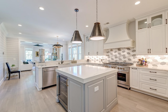 kitchen featuring sink, hanging light fixtures, a kitchen island, custom range hood, and stainless steel appliances