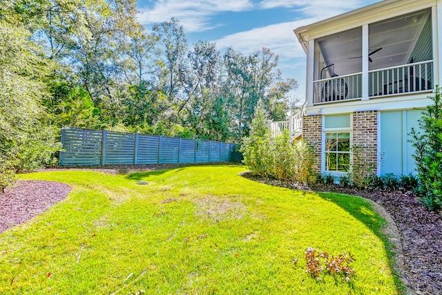 view of yard featuring a sunroom and ceiling fan