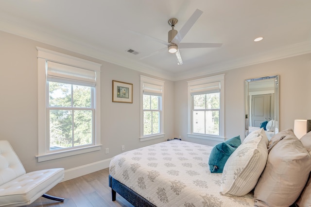 bedroom with ornamental molding, multiple windows, and light wood-type flooring