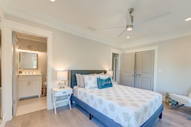 bedroom featuring ceiling fan, light hardwood / wood-style floors, crown molding, ensuite bath, and a closet