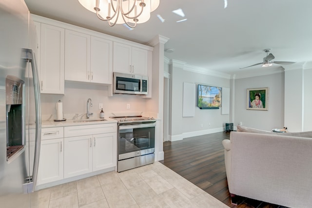 kitchen with stainless steel appliances, white cabinetry, sink, and decorative light fixtures