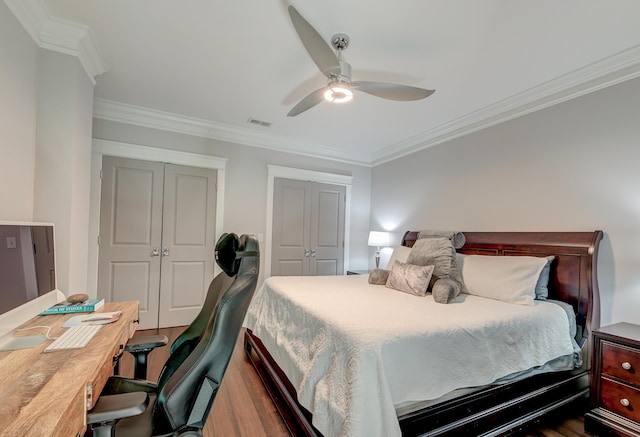 bedroom with crown molding, hardwood / wood-style flooring, and two closets