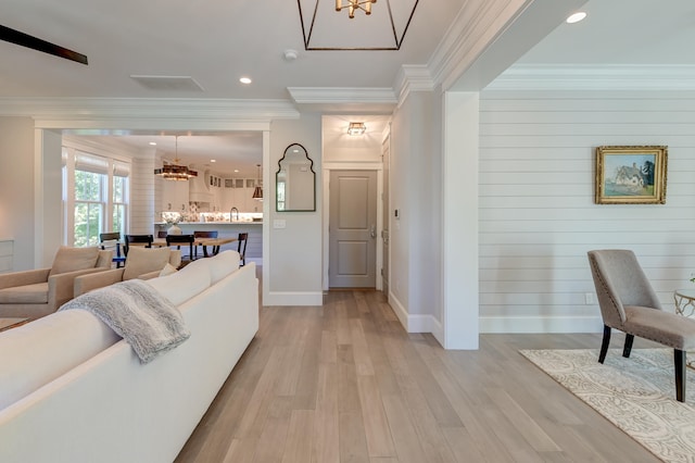 interior space with ornamental molding, a chandelier, and light hardwood / wood-style floors