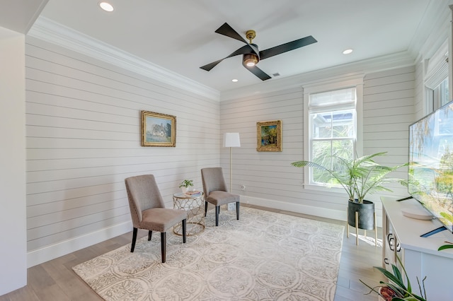 sitting room featuring ceiling fan, ornamental molding, and light hardwood / wood-style flooring