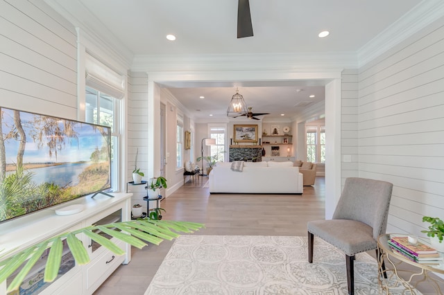 bedroom with crown molding, wooden walls, a fireplace, and light wood-type flooring