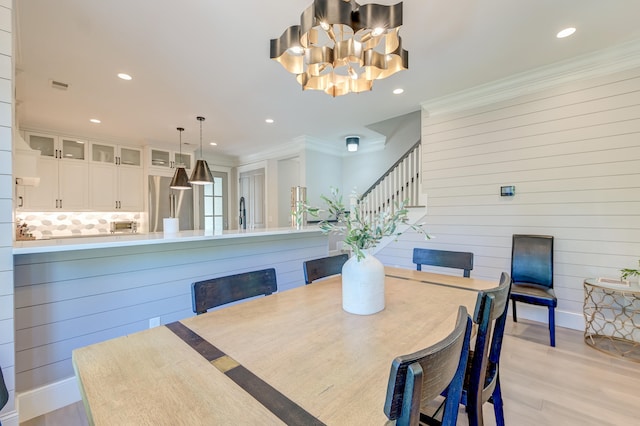 dining area featuring ornamental molding, a chandelier, and light hardwood / wood-style flooring