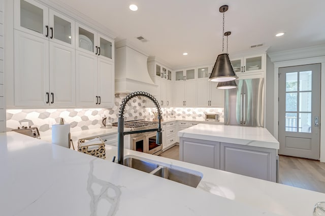 kitchen featuring pendant lighting, tasteful backsplash, white cabinetry, stainless steel fridge, and light stone countertops