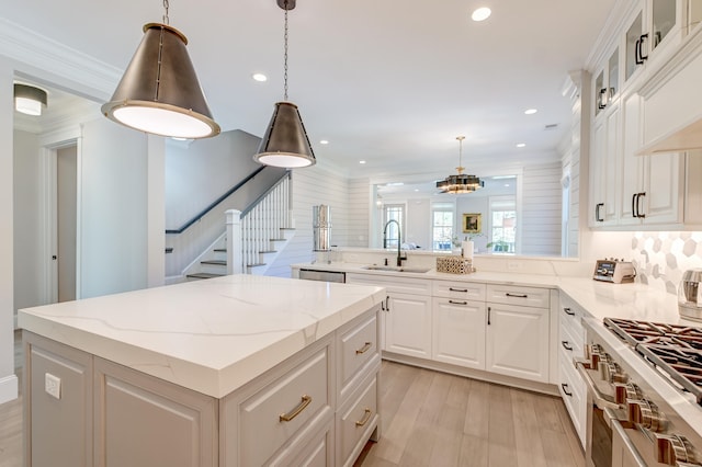 kitchen featuring sink, white cabinetry, a center island, hanging light fixtures, and appliances with stainless steel finishes