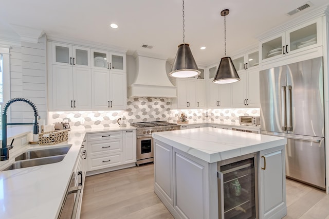 kitchen featuring sink, appliances with stainless steel finishes, custom range hood, a kitchen island, and beverage cooler