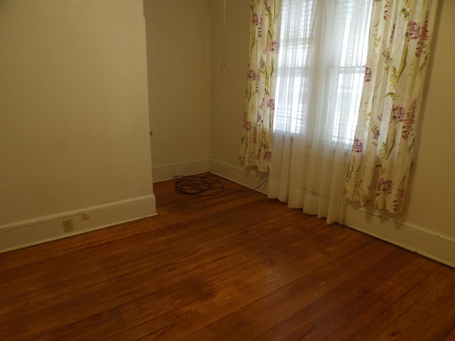 empty room with baseboards and wood finished floors