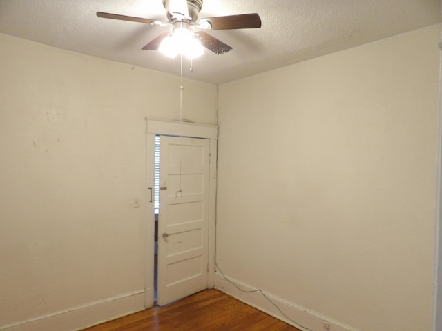 unfurnished room with a textured ceiling, baseboards, and wood finished floors