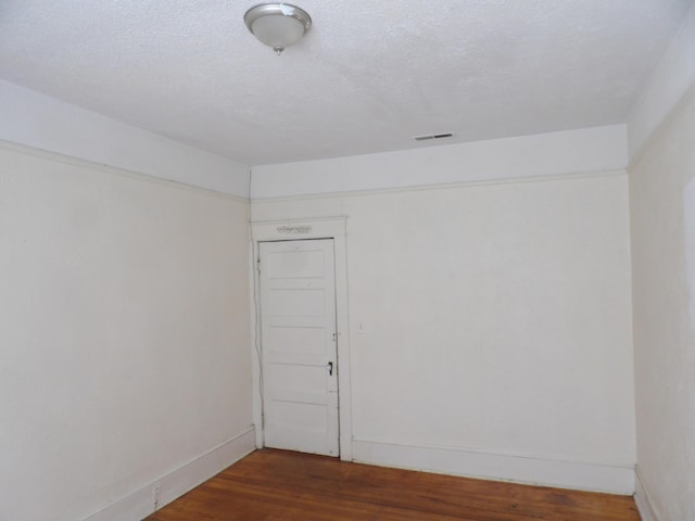 unfurnished room featuring visible vents, a textured ceiling, baseboards, and wood finished floors