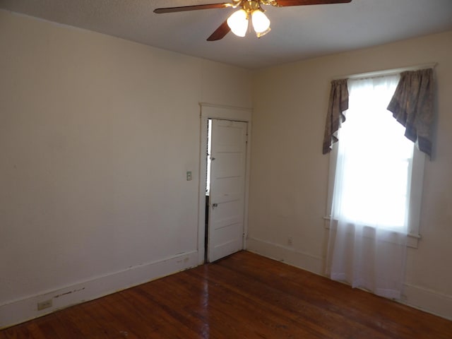 spare room with a wealth of natural light, baseboards, a ceiling fan, and wood finished floors