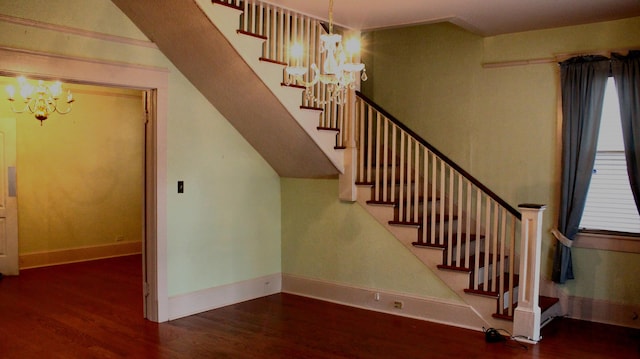 stairway with an inviting chandelier, baseboards, and wood finished floors