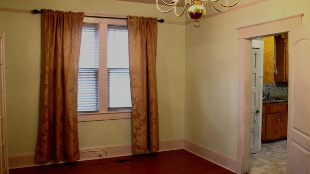 spare room featuring baseboards, a chandelier, and a sink