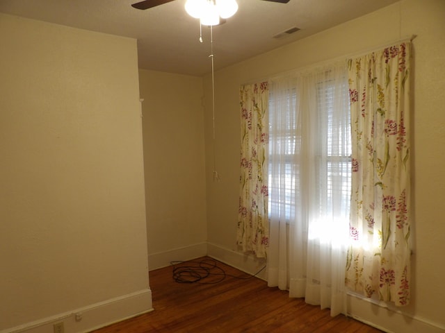 unfurnished room featuring a ceiling fan, visible vents, baseboards, and wood finished floors