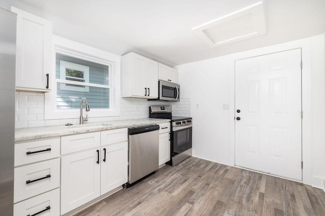 2924 Chicora Ave, North Charleston, SC 29405 - kitchen featuring stainless steel appliances, tasteful backsplash, light wood finished floors, white cabinetry, and light stone counters