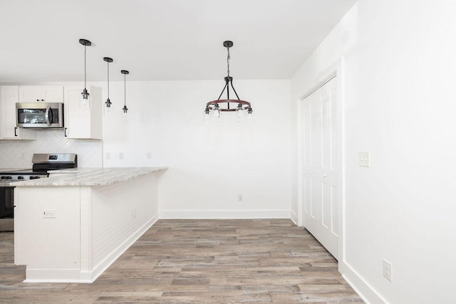 2924 Chicora Ave, North Charleston, SC 29405 - kitchen with stainless steel appliances, decorative backsplash, light wood-style floors, and decorative light fixtures