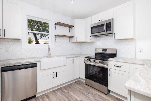 2924 Chicora Ave, North Charleston, SC 29405 - kitchen featuring appliances with stainless steel finishes, open shelves, light stone countertops, and white cabinetry