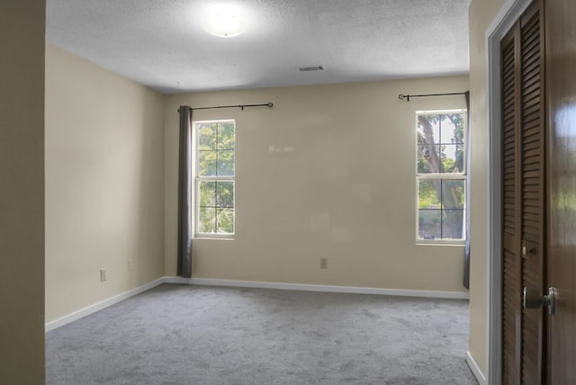 carpeted empty room with a textured ceiling