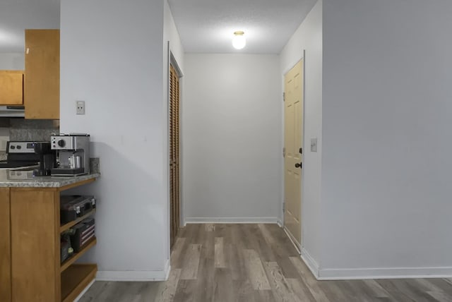 corridor featuring light wood-type flooring and a textured ceiling