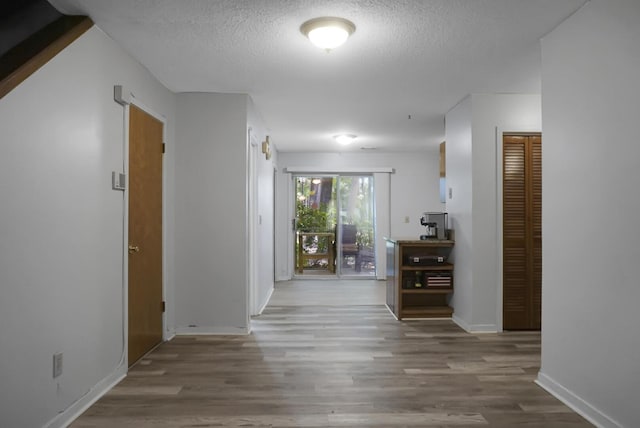 hall with hardwood / wood-style floors and a textured ceiling