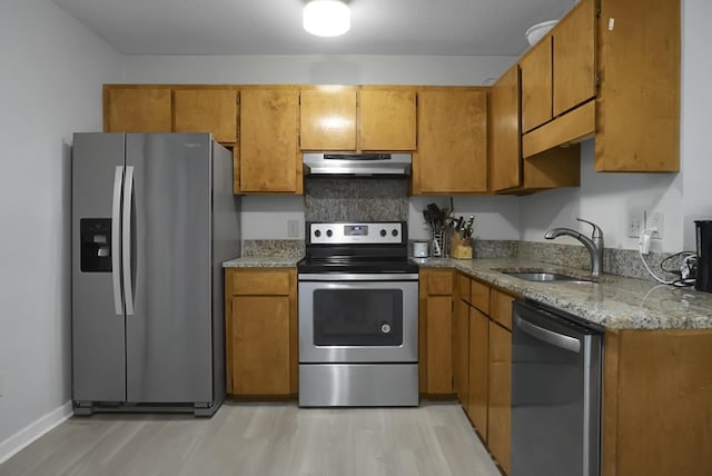 kitchen with backsplash, sink, light stone countertops, light hardwood / wood-style floors, and stainless steel appliances