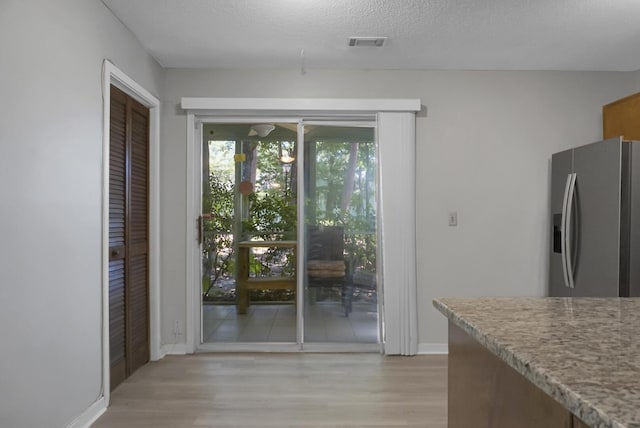 doorway with light hardwood / wood-style floors and a textured ceiling