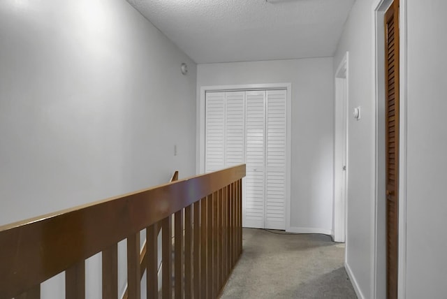 hall with light colored carpet and a textured ceiling