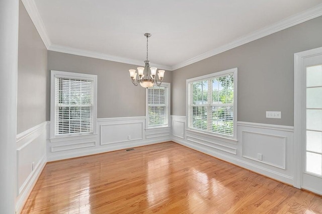 unfurnished dining area with ornamental molding, a chandelier, and light hardwood / wood-style floors