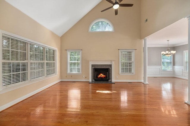 unfurnished living room featuring decorative columns, ceiling fan with notable chandelier, a high end fireplace, and light hardwood / wood-style floors