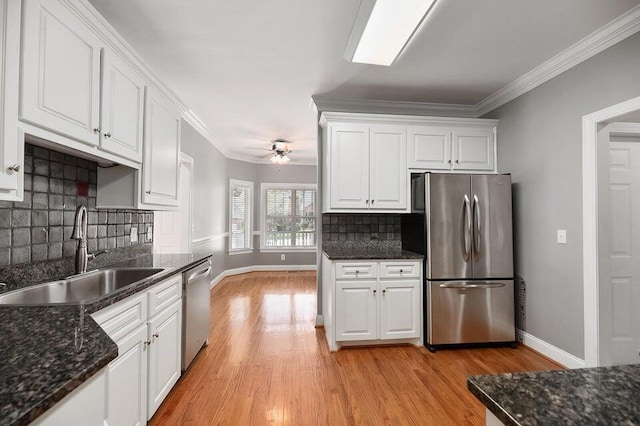 kitchen with ornamental molding, appliances with stainless steel finishes, sink, and white cabinets