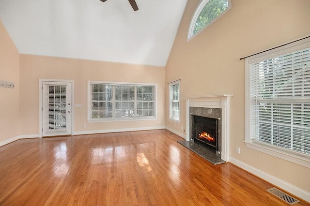 unfurnished living room featuring a premium fireplace, high vaulted ceiling, ceiling fan, and light hardwood / wood-style floors