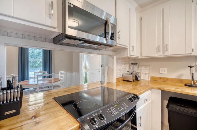 kitchen featuring black range, white cabinetry, butcher block counters, and backsplash