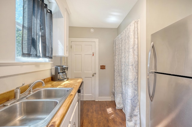 kitchen with appliances with stainless steel finishes, sink, dark wood-type flooring, and wooden counters