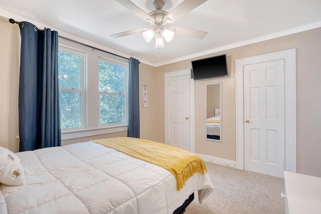 carpeted bedroom with ornamental molding and ceiling fan