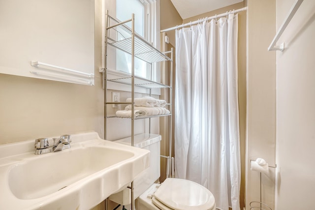 bathroom with curtained shower, toilet, and sink